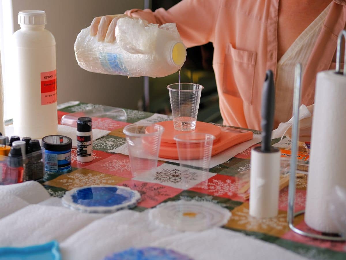 woman pouring resin in a cup to do coasters to grow as an artist